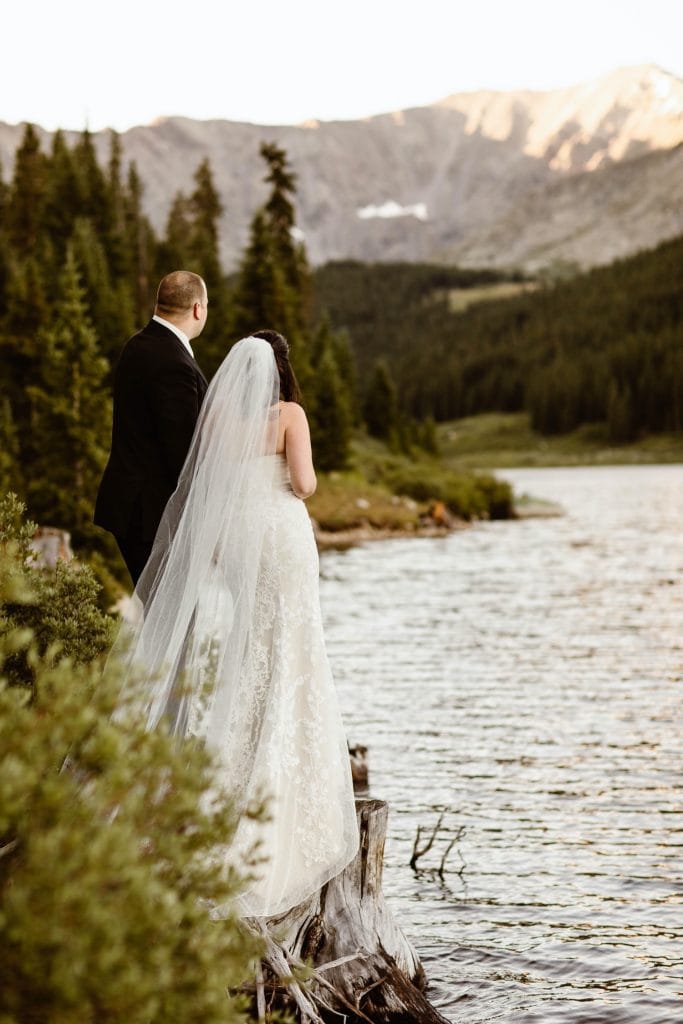 destination elopement couple standing by the lake and admiring the mountain view