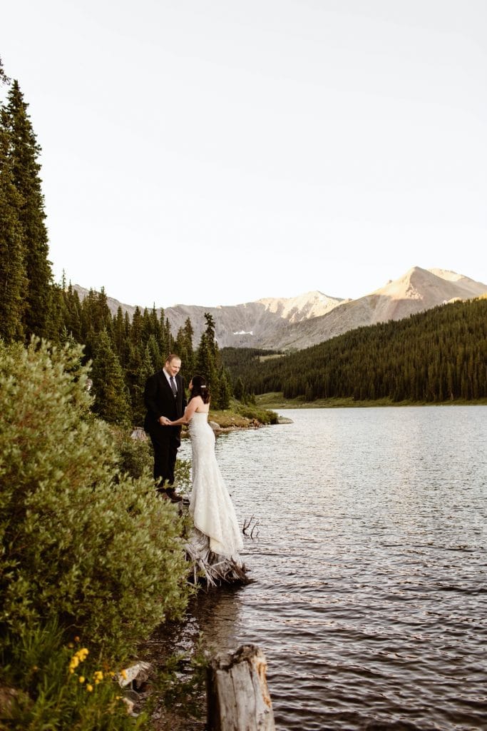 destination elopement couple standing by the lake and admiring the mountain view