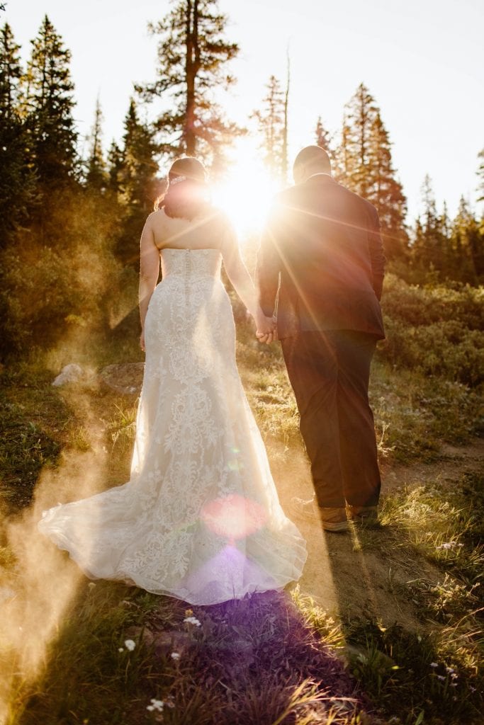 couple walking down a trail at sunrise after their elopement ceremony