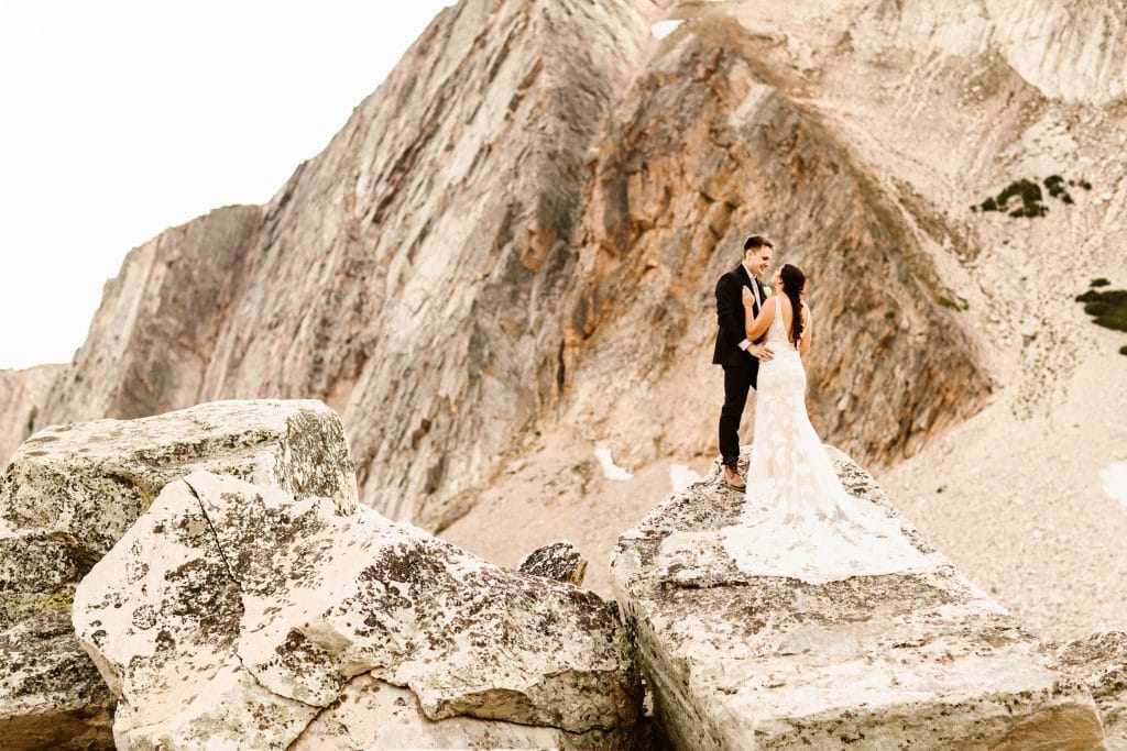 elopement advice | couple standing on a rocky granite mountain on their elopement day