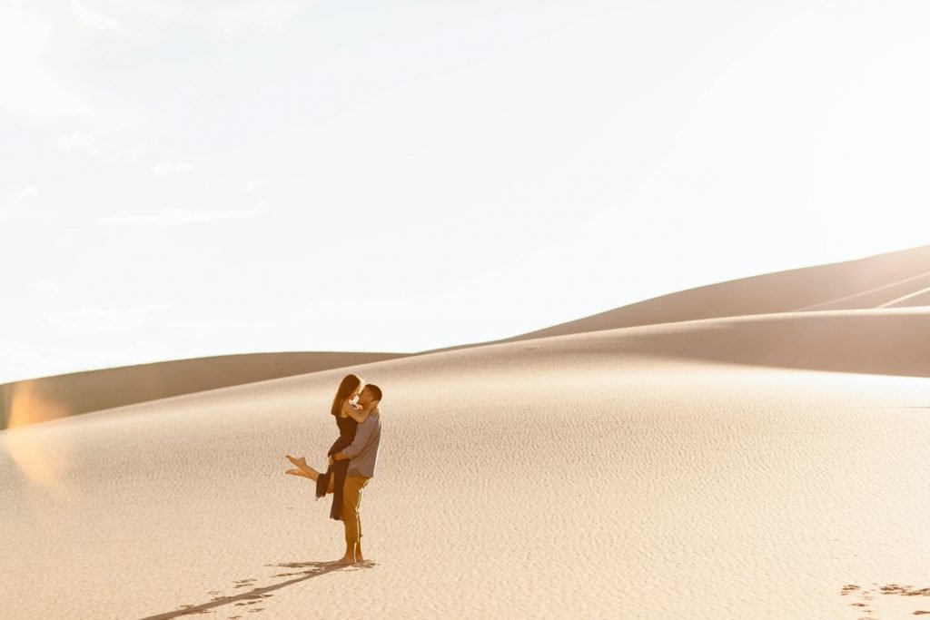 guy lifting girl up at the sand dunes