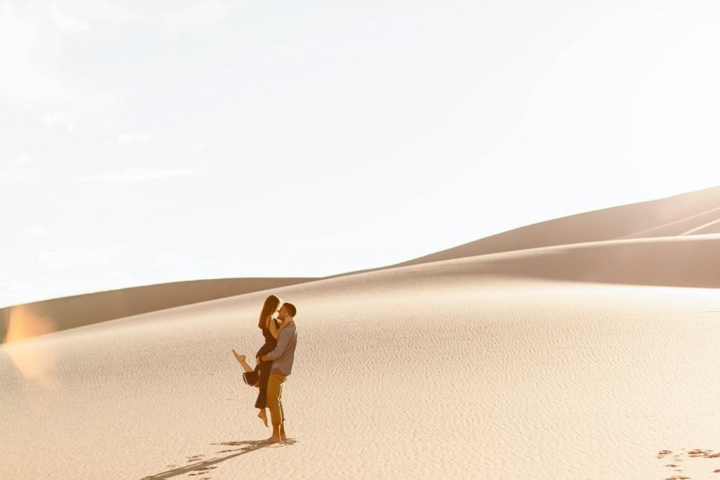 guy lifting girl up at the sand dunes