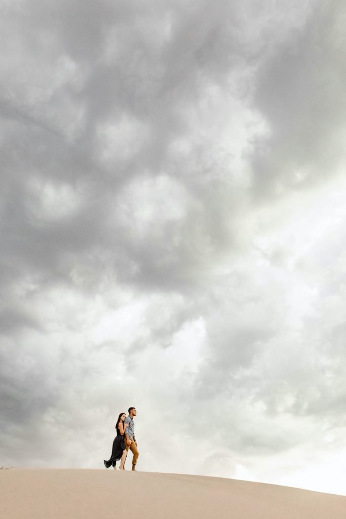 sand dunes engagement photos taken at sunset with giant storm clouds