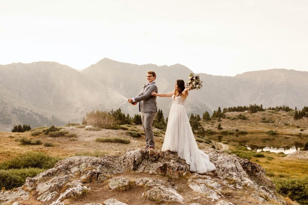 couple popping champagne during their sunrise elopement near Keystone