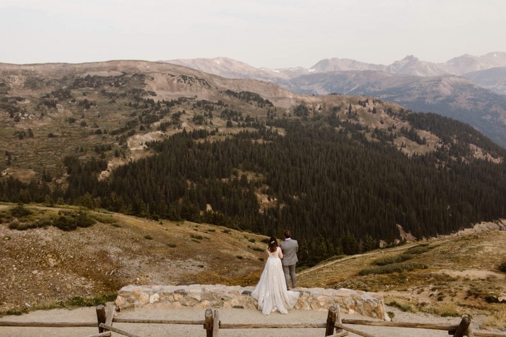bride and groom looking out onto the hazy Rocky Mountains after their sunrise elopement