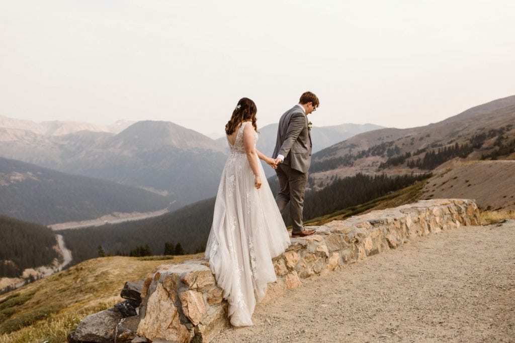 bride and groom looking out onto the hazy Rocky Mountains after their sunrise elopement