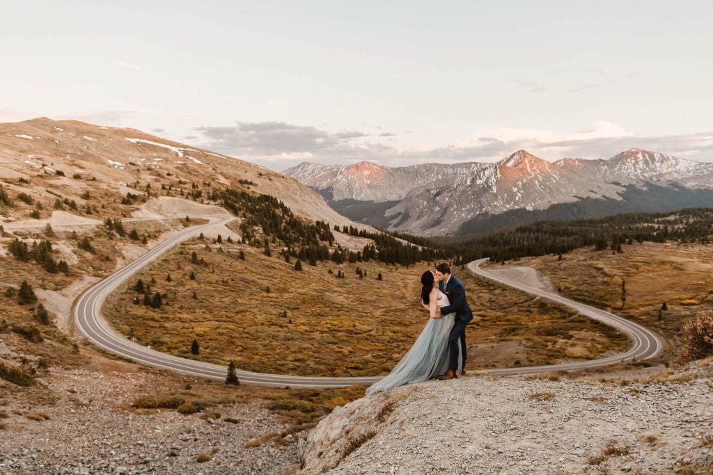 Buena Vista elopement couple kissing on the edge of a cliff overlooking a giant switchback curve in the road