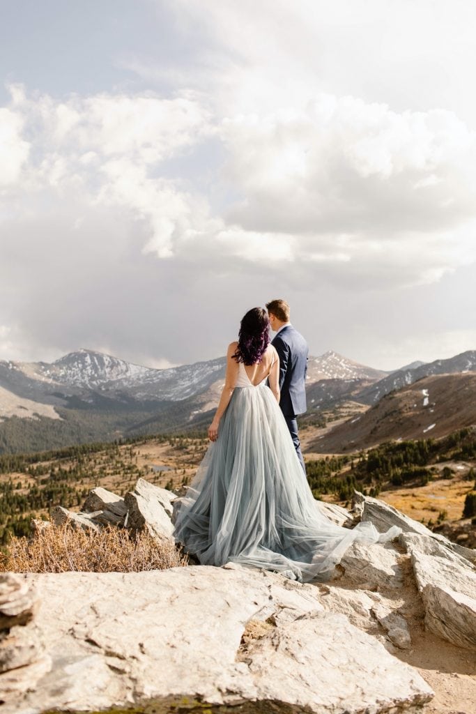 bride and groom standing on a cliffside as the wind blows by on their Buena Vista elopement day