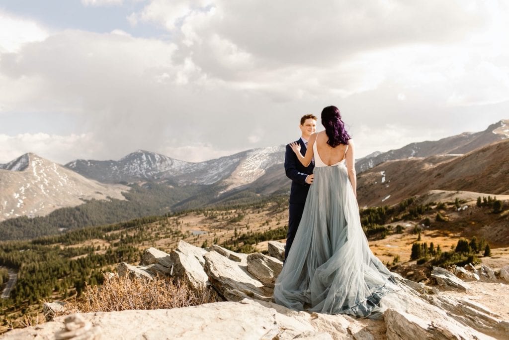 bride and groom standing on a cliffside as the wind blows by on their Buena Vista elopement day