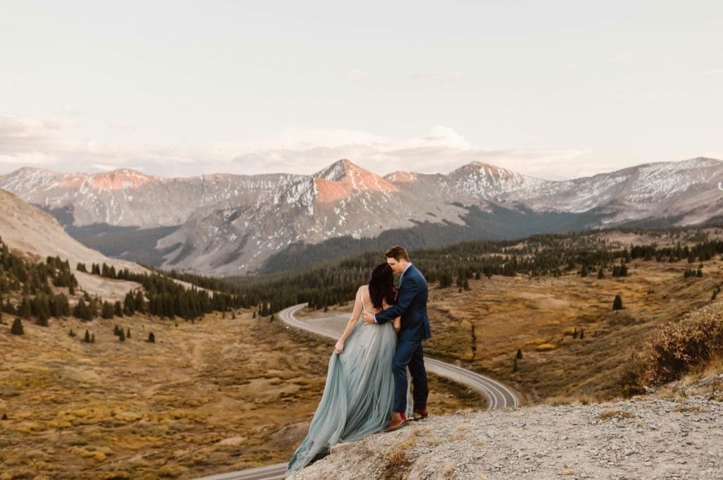Buena Vista elopement couple standing on the edge of a cliff overlooking a giant switchback curve in the road