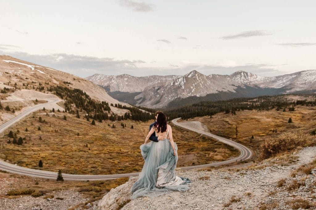 Buena Vista elopement couple standing on the edge of a cliff overlooking a giant switchback curve in the road