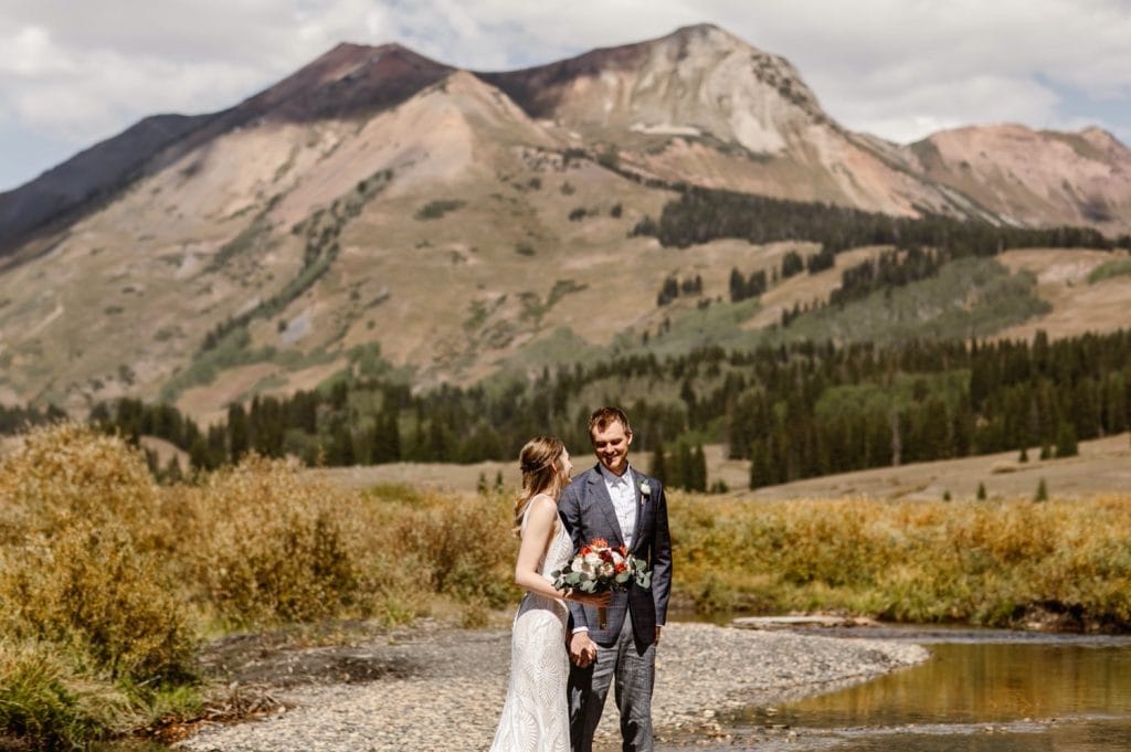 bride and groom standing together by the East River during their Crested Butte elopement ceremony