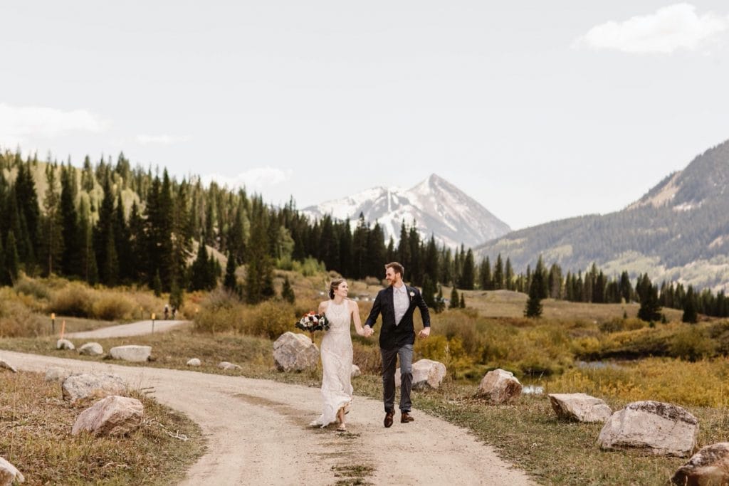 Crested Butte elopement couple running down a dirt road in the mountains