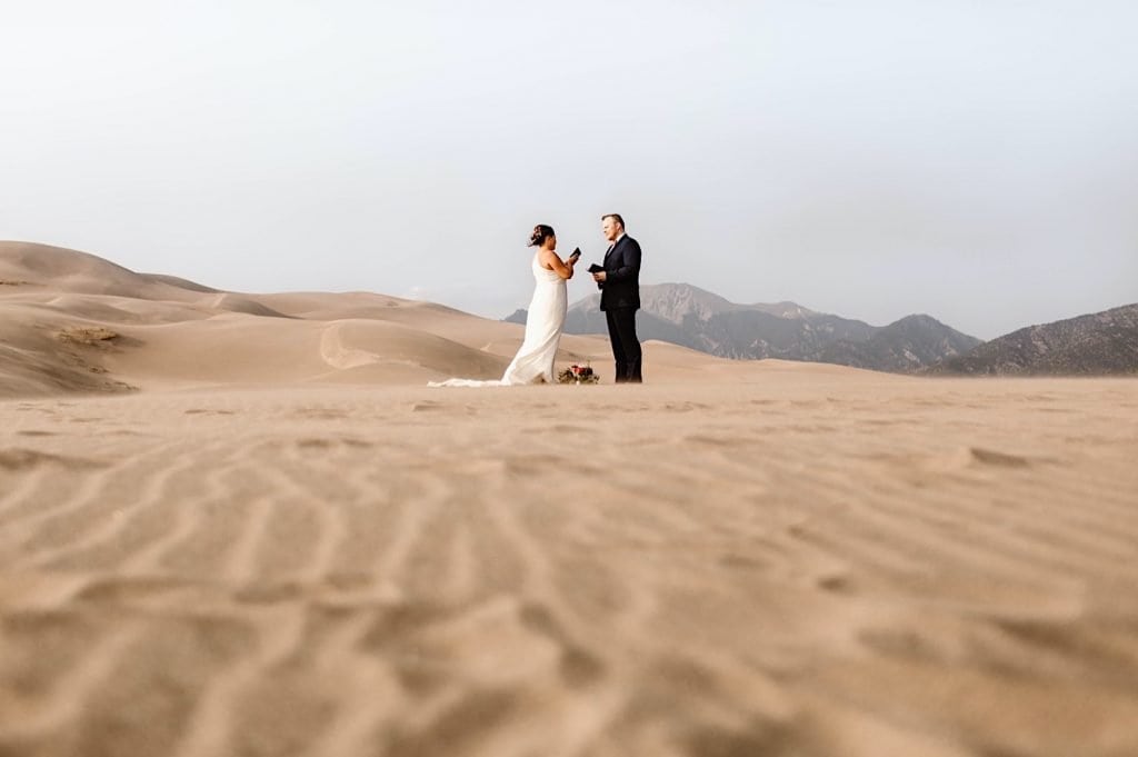 bride and groom reading notes from non-present family members during their Great Sand Dunes National Park elopement ceremony