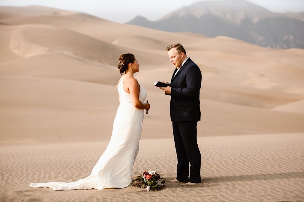 groom reading his vows to the bride during their Great Sand Dunes National Park elopement ceremony