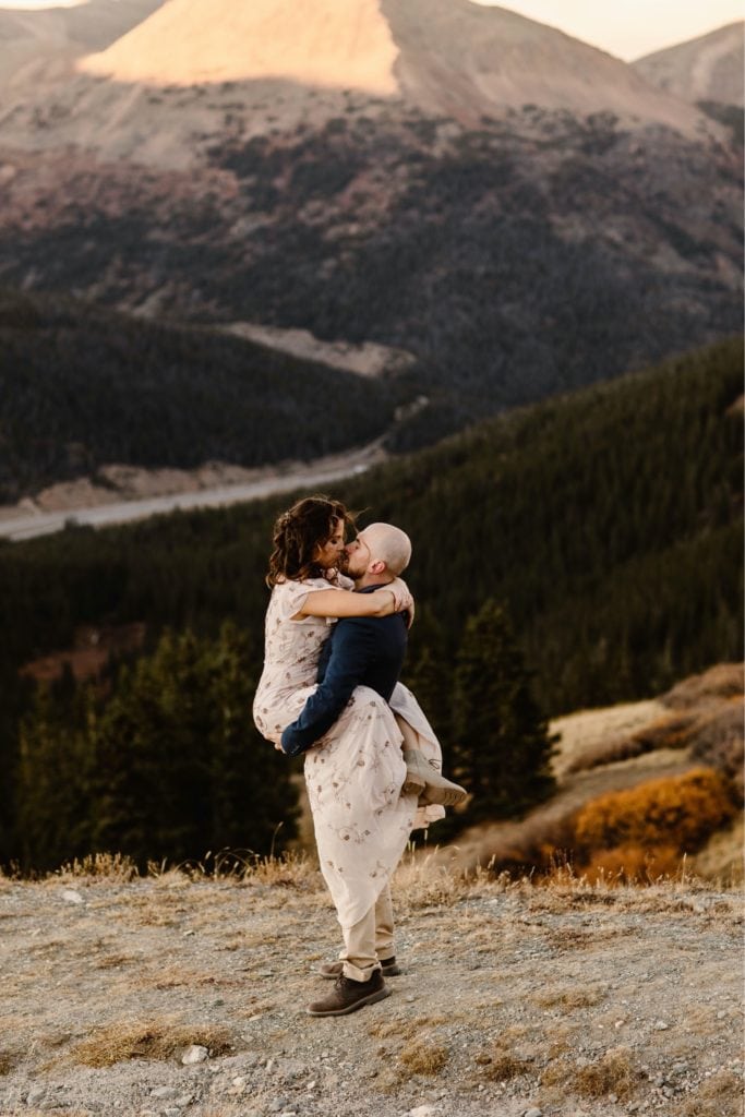 groom lifting bride up while they kiss in the mountains of Colorado