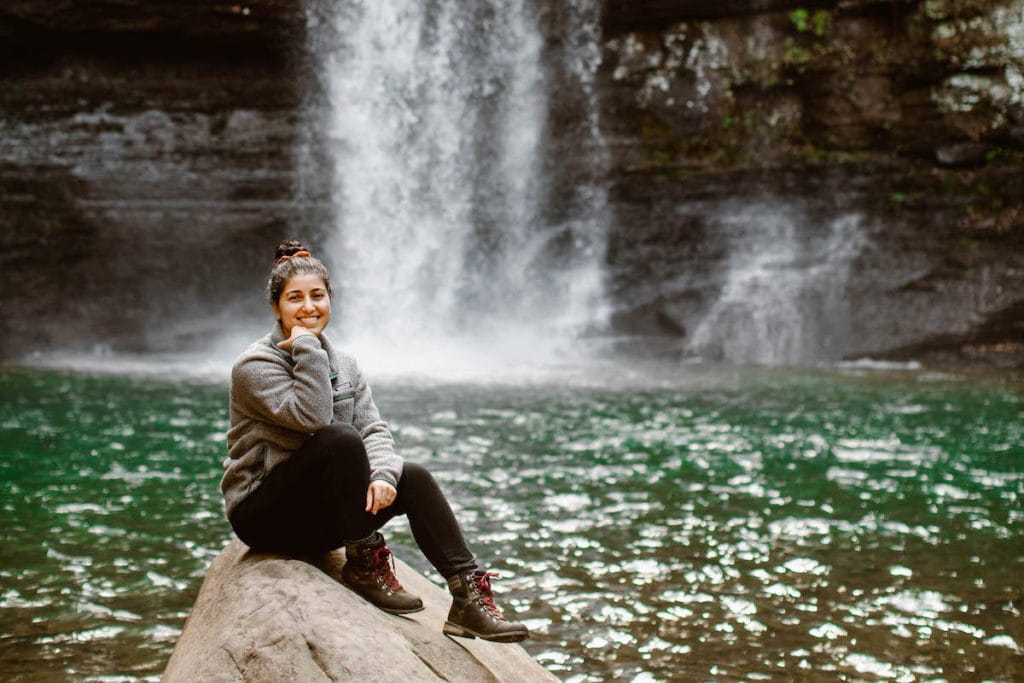 photographer sitting by a waterfall in the mountains | adventure elopement packages
