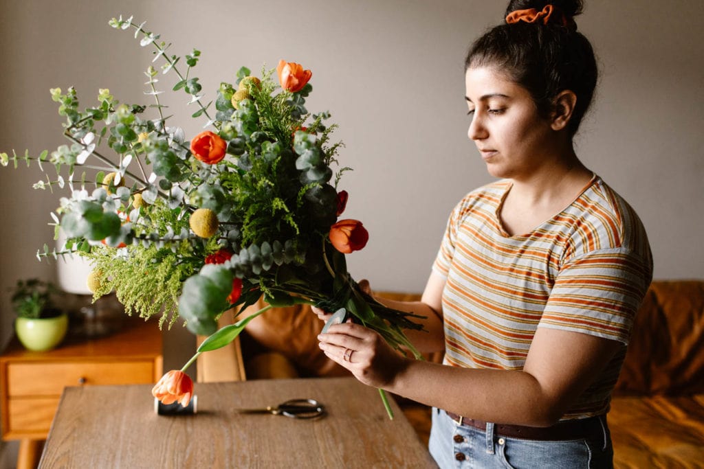 woman showing how to secure a diy bouquet with green floral tape