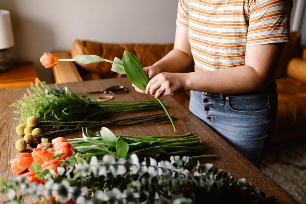 woman showing how to prep the stems for a diy wedding bouquet