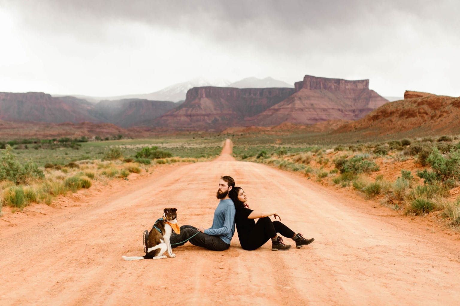 best things to do in Moab Utah cover photo of a couple sitting on a desert dirt road off Utah 128