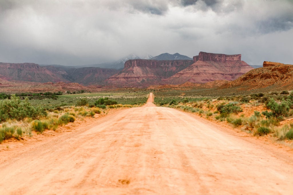 dirt backroad in Moab Utah with view of the La Sal mountains in a storm