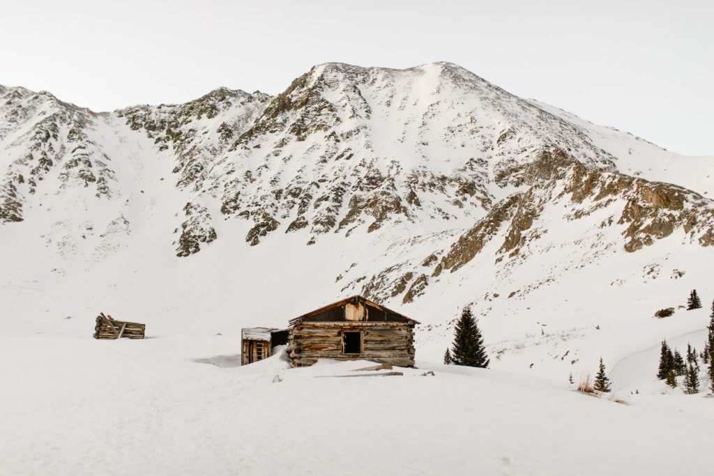 view of a ramshackle cabin against a snowy mountains during the best time to visit Colorado in the winter