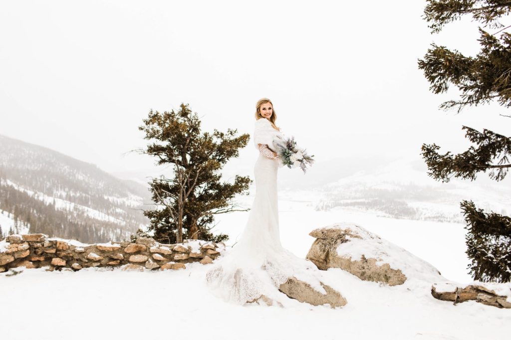 bride wearing a bright white winter wedding shawl in the snow