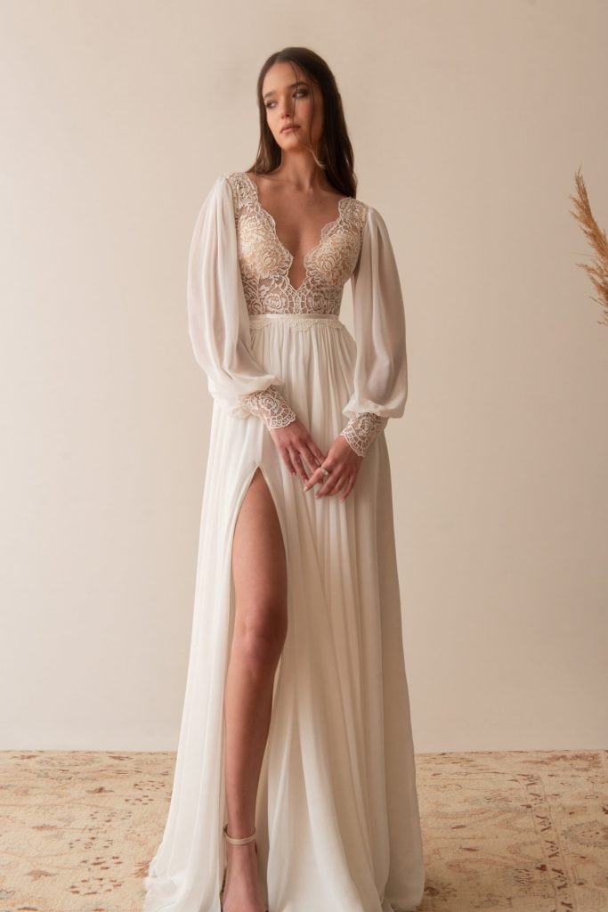 bride wearing a chiffon and lace long sleeve elopement dress with a plunging neckline and high slit