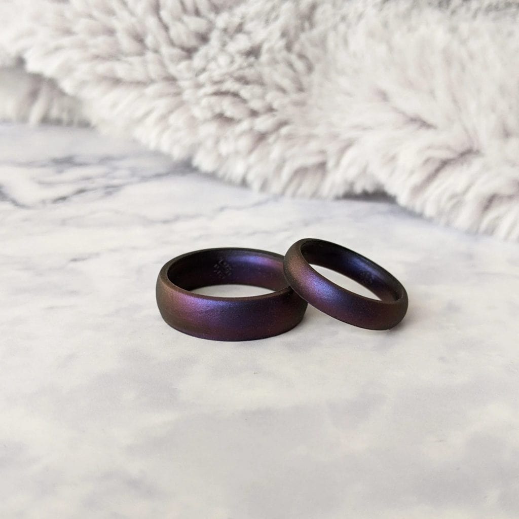 glimmering cosmic purple best wedding bands for men and women sitting stacked next to one another