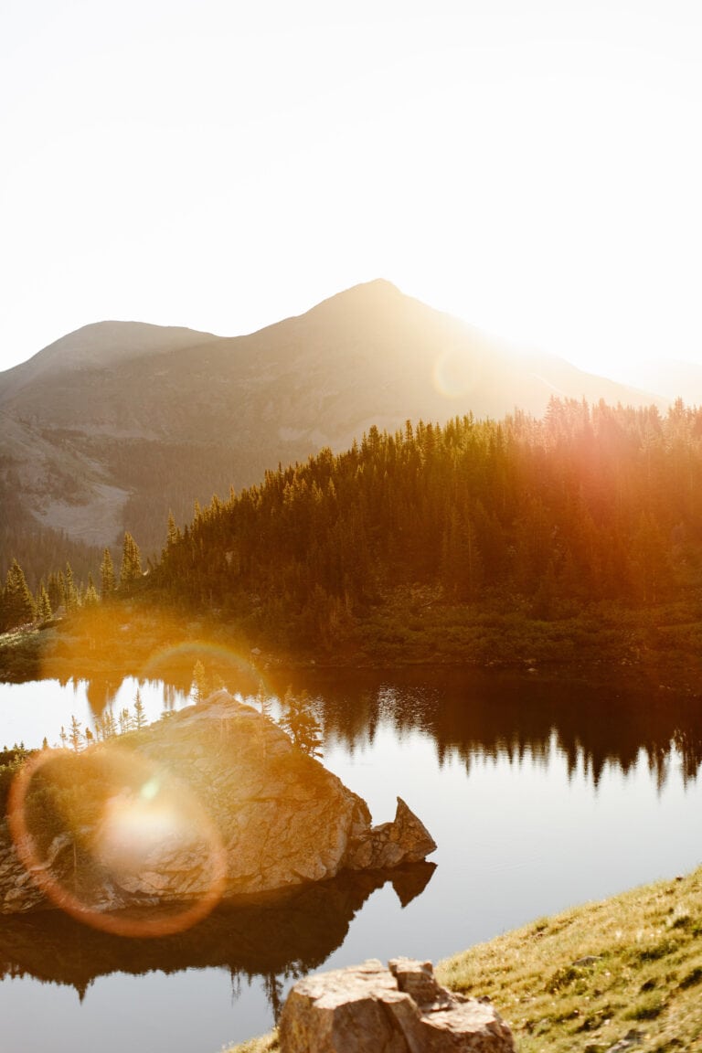Colorado alpine lake with glowing sunrise light washing over the water
