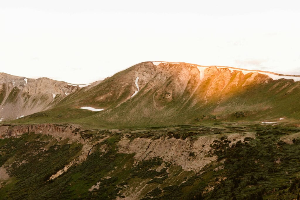 orange alpenglow hitting the ridge of a mountain on Independence Pass in Colorado