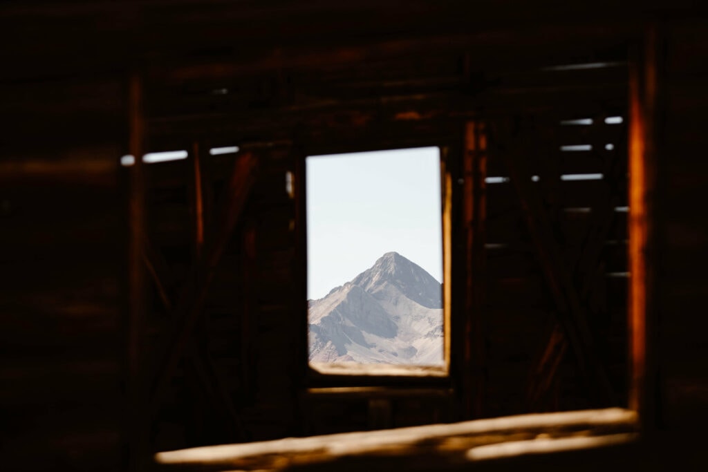 view of the mountains through a window frame in Alta ghost town near Alta Lakes Telluride
