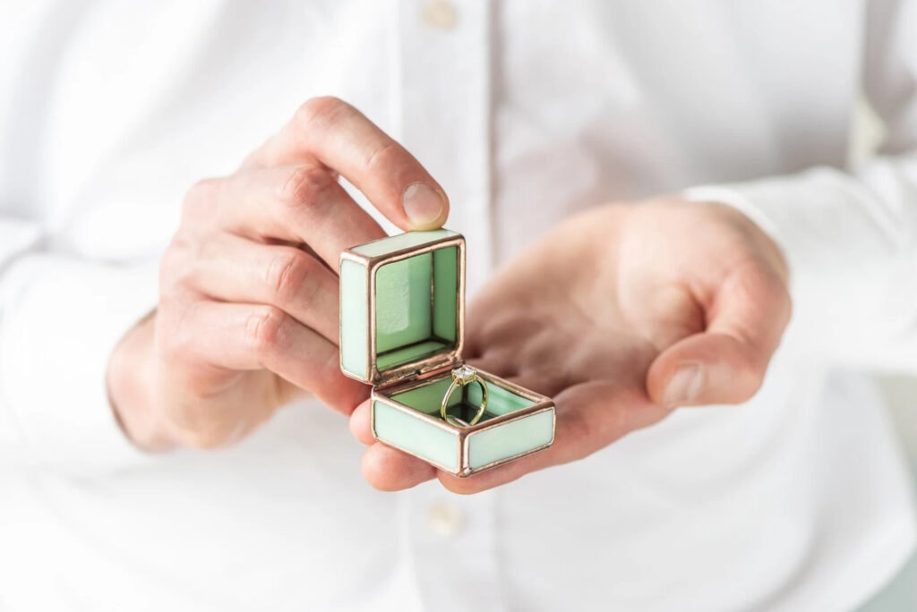 man holding a vintage style green glass unique wedding ring box for an engagement
