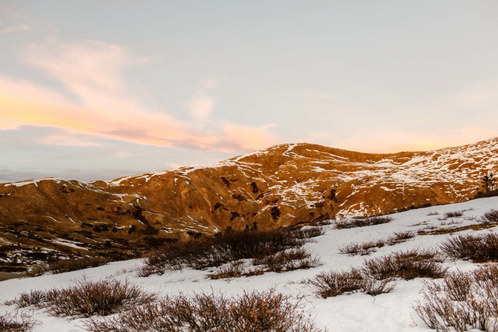 fall sunset on Loveland Pass with pink hued clouds and snow on the ground