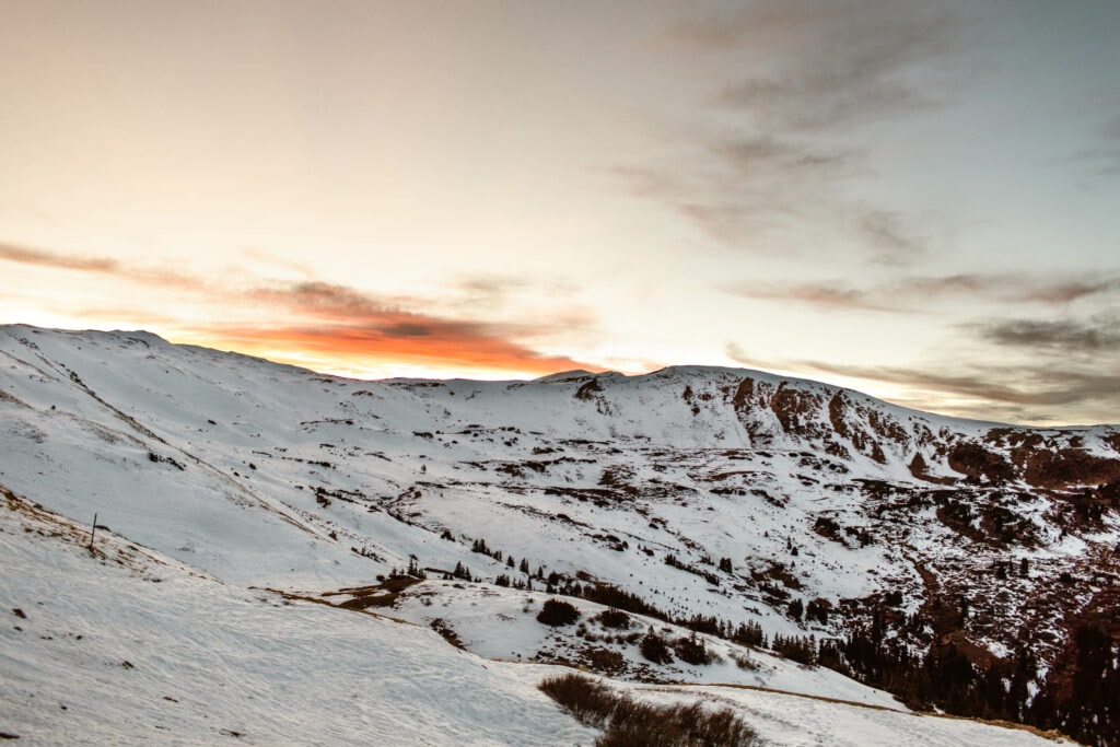 view of a rainbow colored sunset on the snowy mountains near the continental divide overlook on Loveland Pass