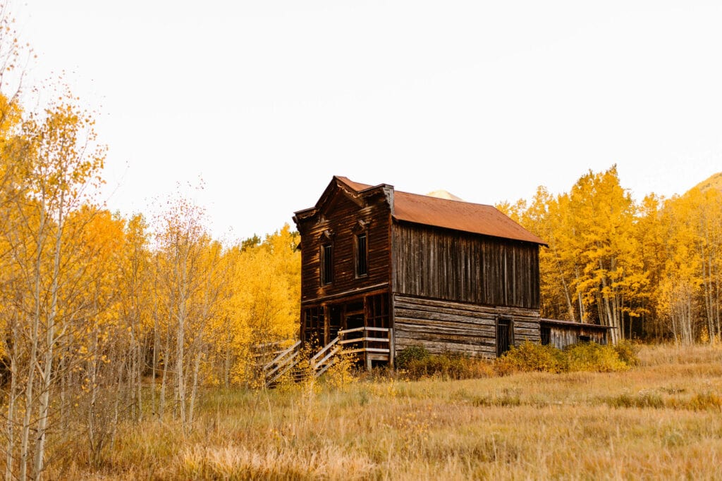 abandoned two story Ashcroft Ghost Town hotel surrounded by golden aspen trees