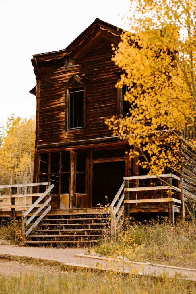 abandoned wooden hotel with yellow aspen trees surrounding it in Ashcroft Ghost Town Colorado
