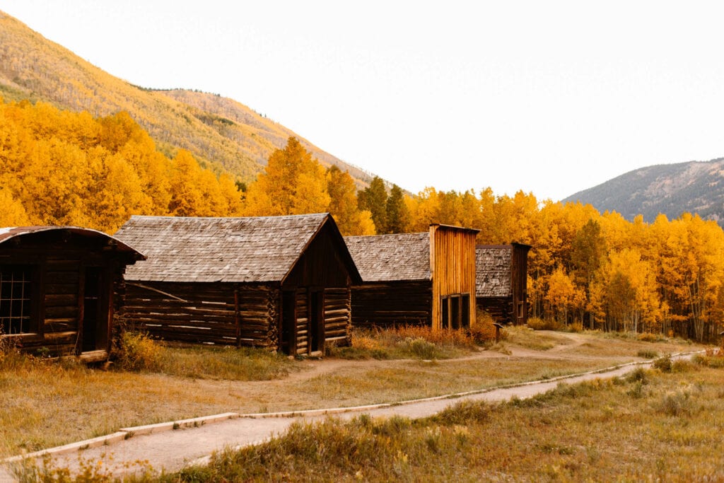 a row of late 1800s log cabin style buildings along the gravel pathway in Ashcroft Ghost Town near Aspen CO