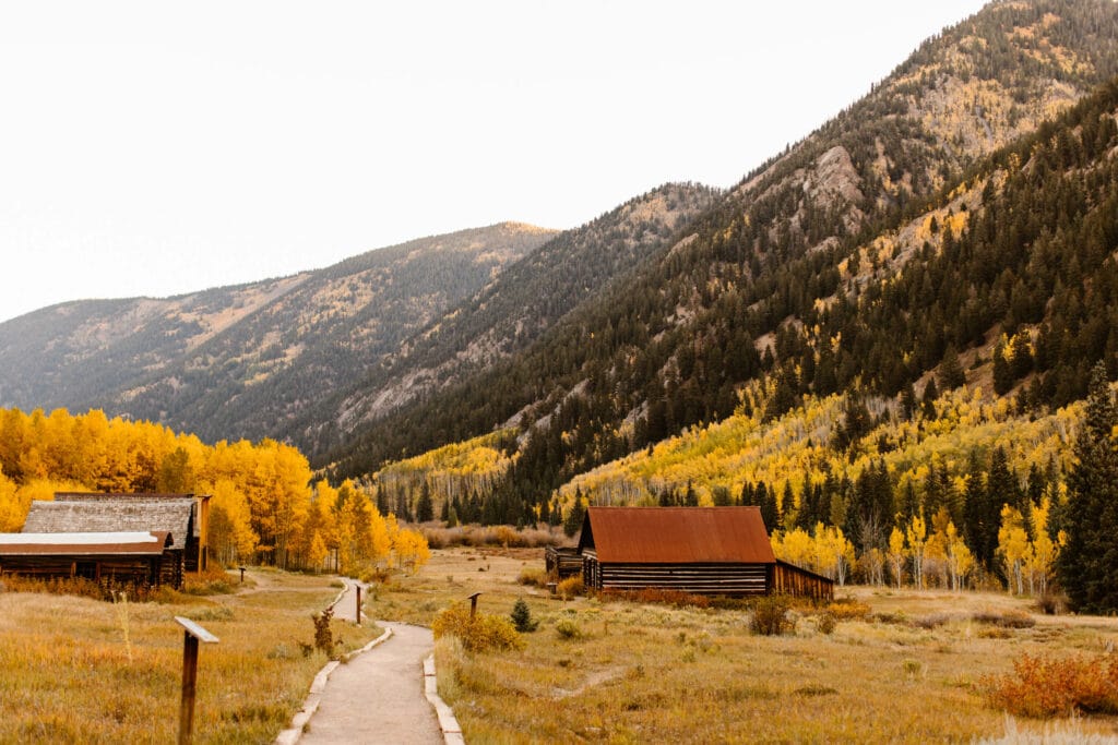 gravel pathway leading through Ashcroft Ghost Town Colorado with aspen dotted mountains in the background