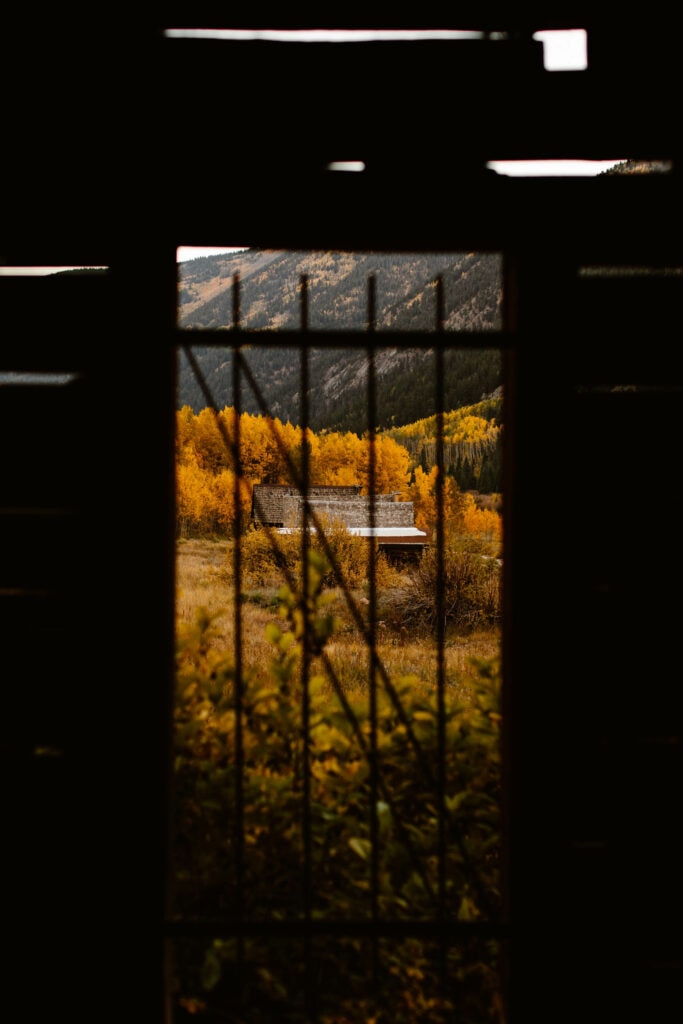 view of an abandoned building in Ashcroft Ghost Town from behind jail bars on a window