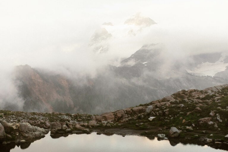 view of Mt Shuksan and the Kulshan Ridge shrouded in fog with a pond in the foreground at Artist Point Mt Baker in Washington