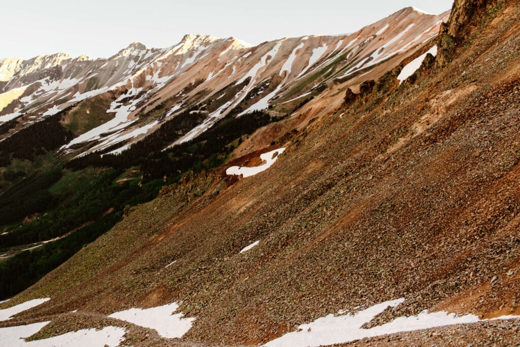 red hued mountains on Ophir Pass in Colorado with snow dotting them