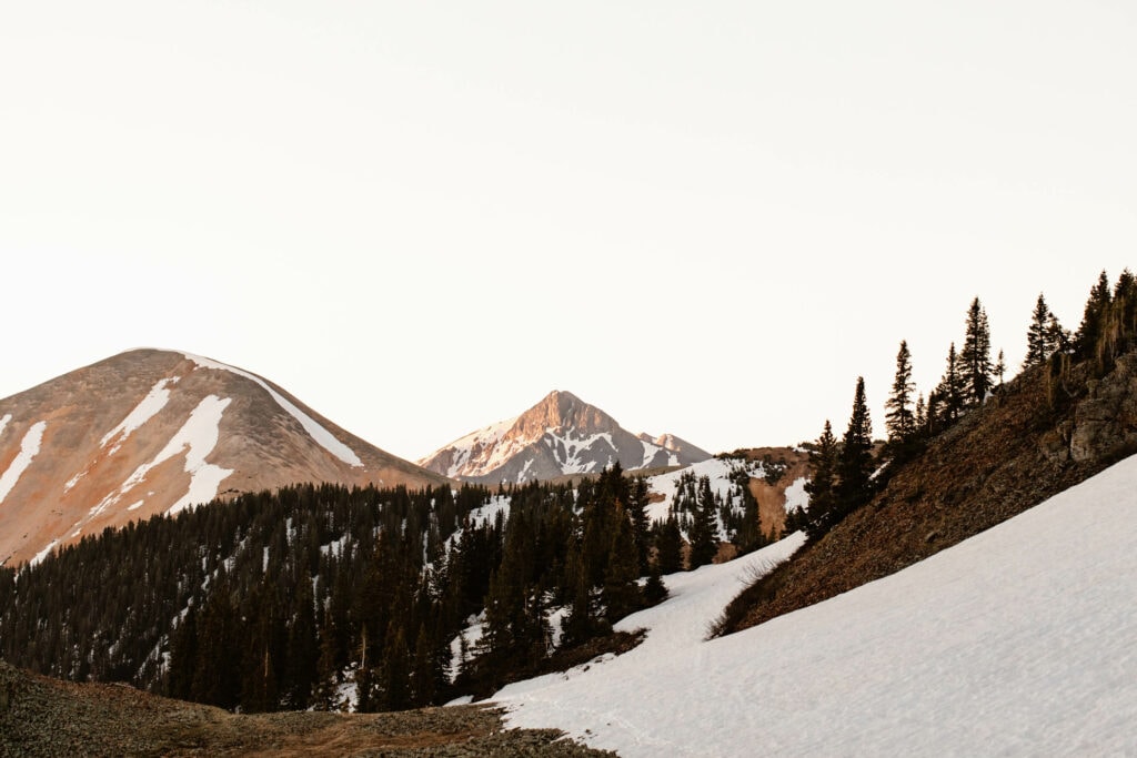 alpenglow hitting the top of a snowy mountain that can be seen from the summit of Ophir Pass CO