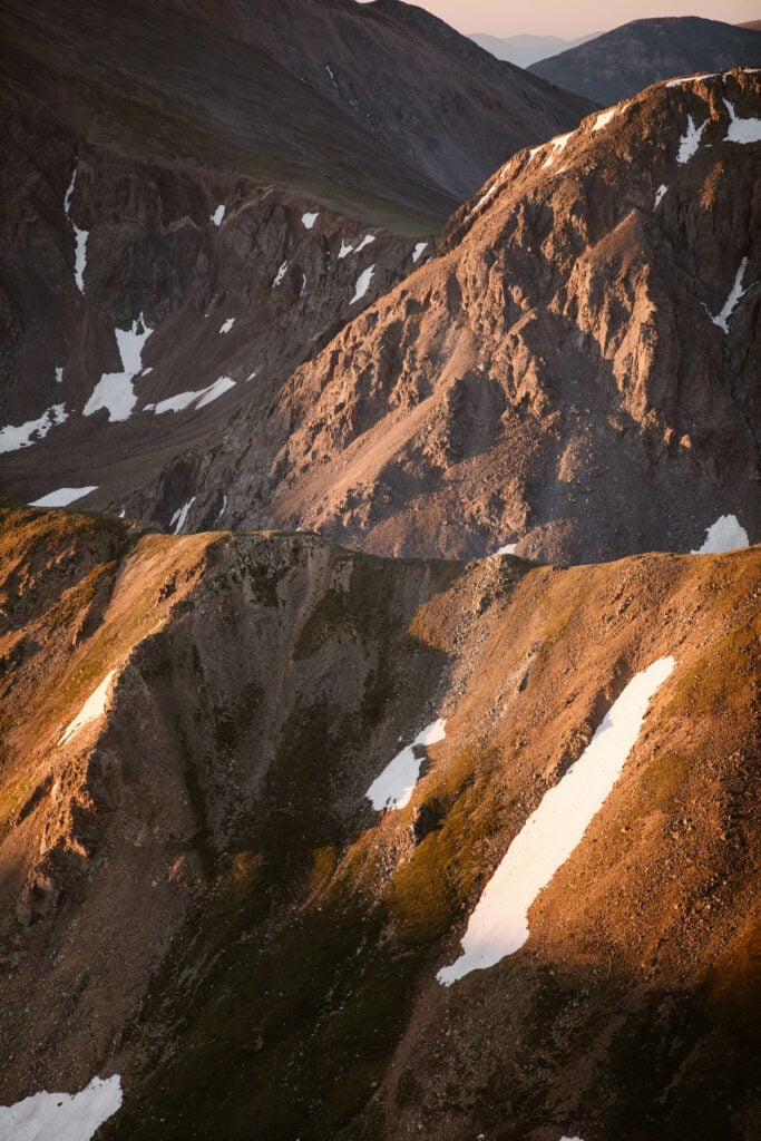 layers of mountains with alpenglow on them on the Mount Sniktau hike trail in Colorado