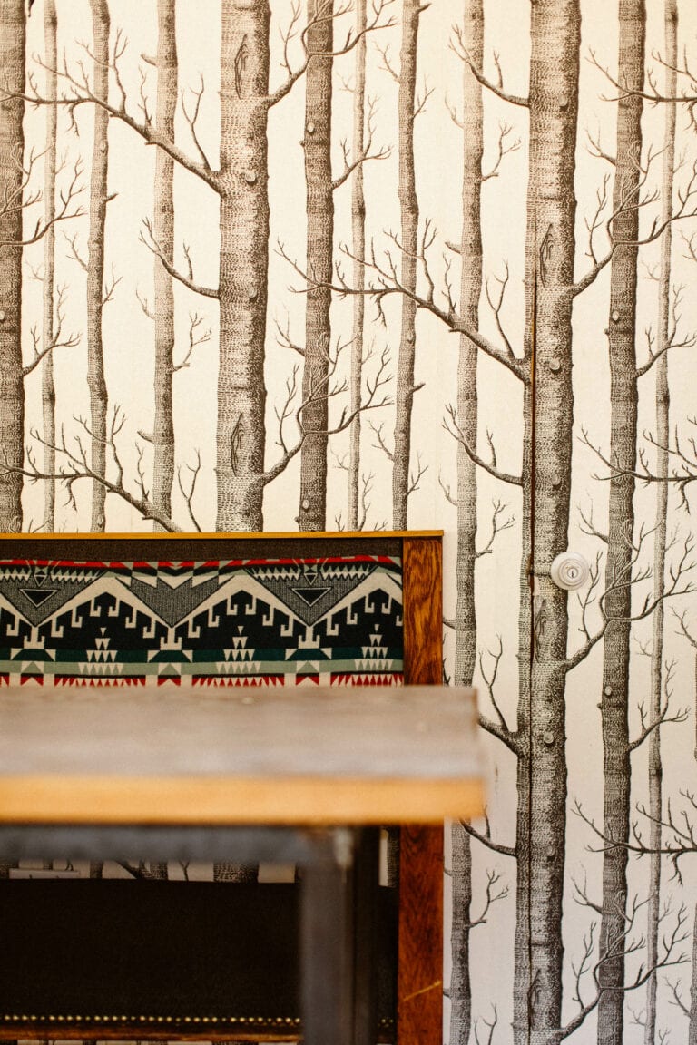 booth seating at Plume Coffee Bar with a Navajo inspired print on the seats and a forest pattern wallpaper in the background