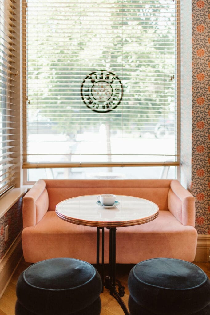 pink velvet couch and round white cafe table in a cozy window nook in Felix Roasting Company in Aspen, CO