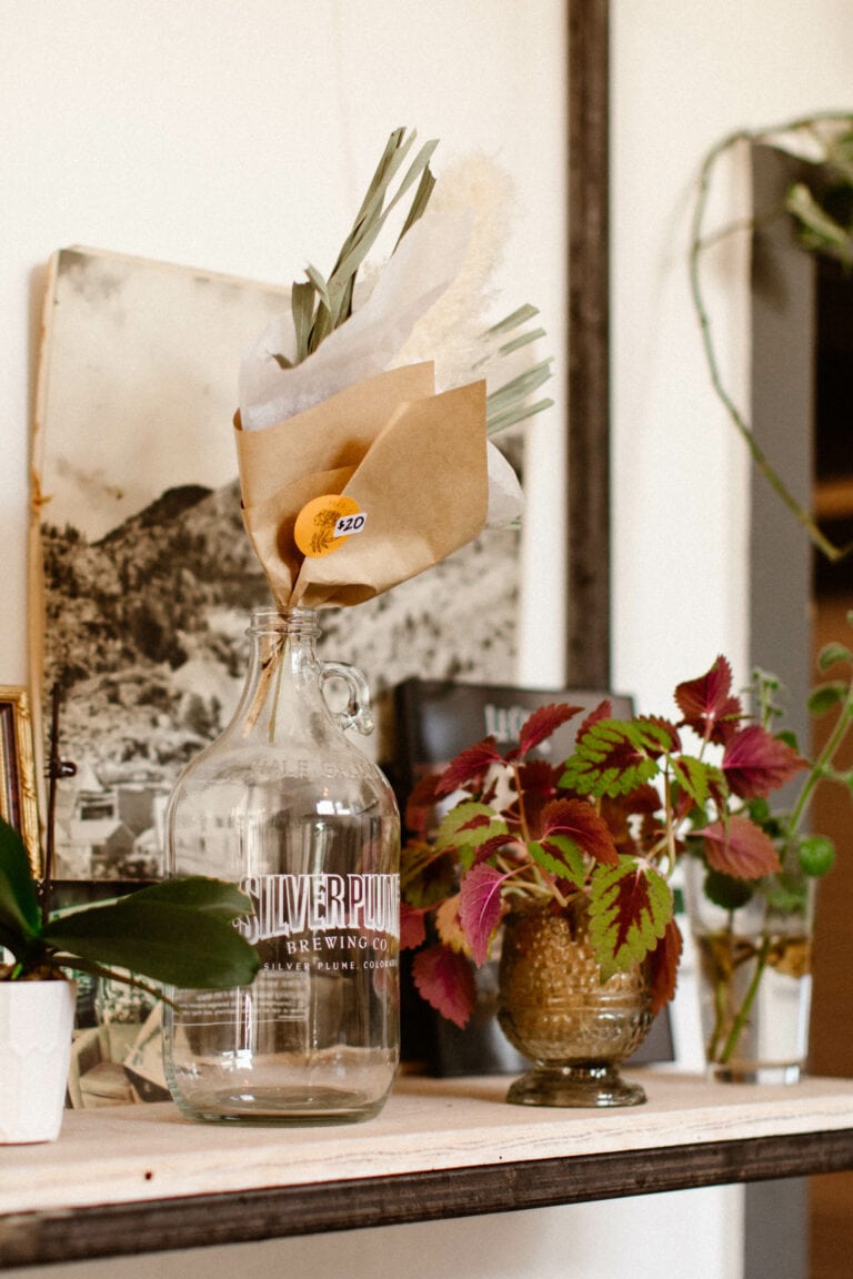vintage decor on a shelf including a growler containing dried flowers